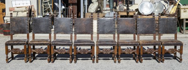 Gruppo di otto sedie legno lavorato con bulloni rivestimento cuoio seduta rovinata Italia 1930